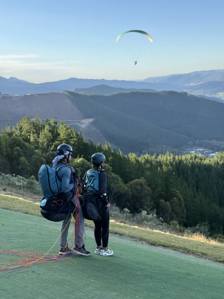 Paragliden in Australië, VA Britt wacht voor opstijgen op groene mat, bergen en andere paraglider op achtergrond